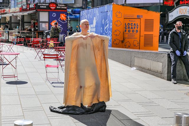 A photo of a man in a robe dancing in Times Square